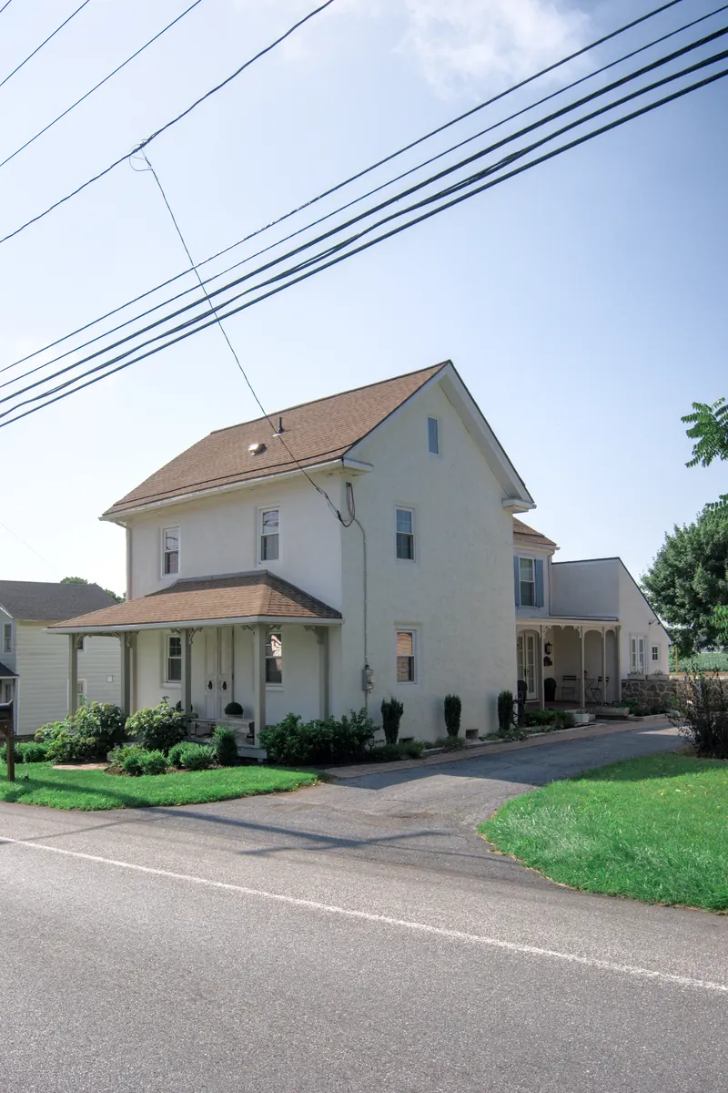 The house in three-quarter view from the road, its porch and the drive running back along the side.